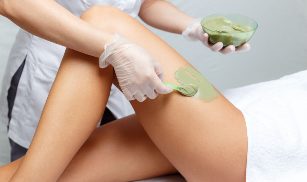 Cosmetologist applies seaweed mud on a woman's hip in a cosmetological beauty clinic