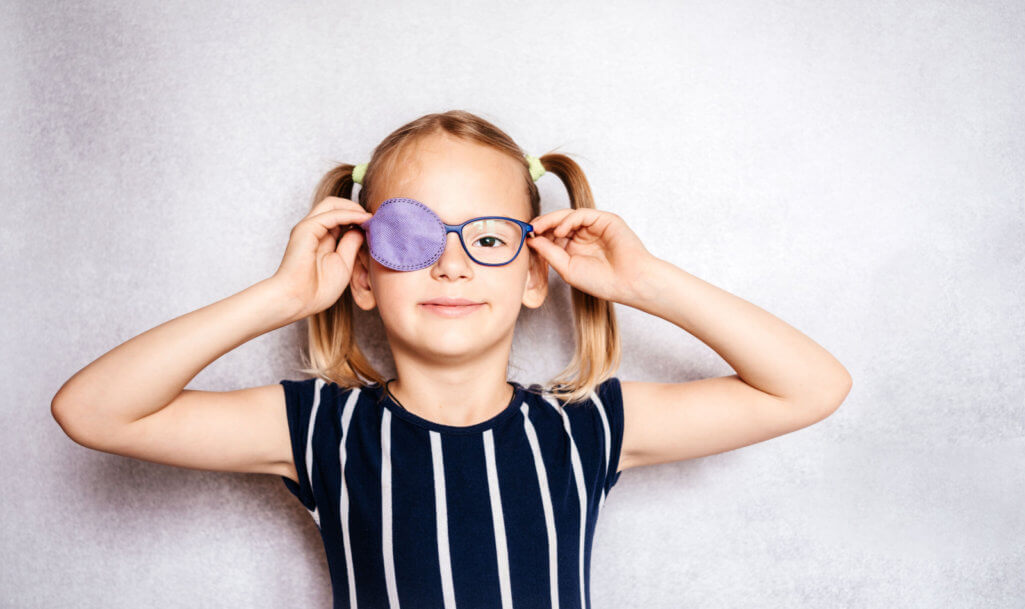 Happy little girl wearing glasses and eye patch or occluder, amblyopia (lazy eye) treatment