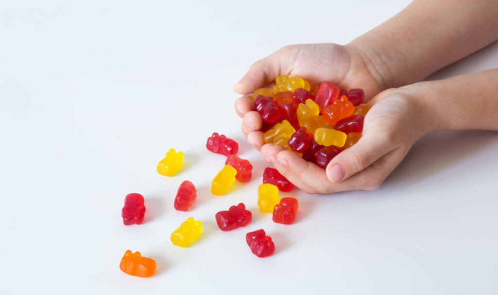 kid's hands with colored gummi bears, chewing vitamins, healthy candies