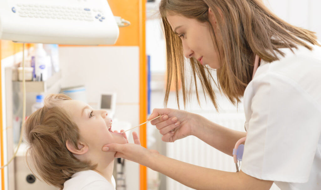 Cute boy being checked for staphylococcus in throat in a clinic