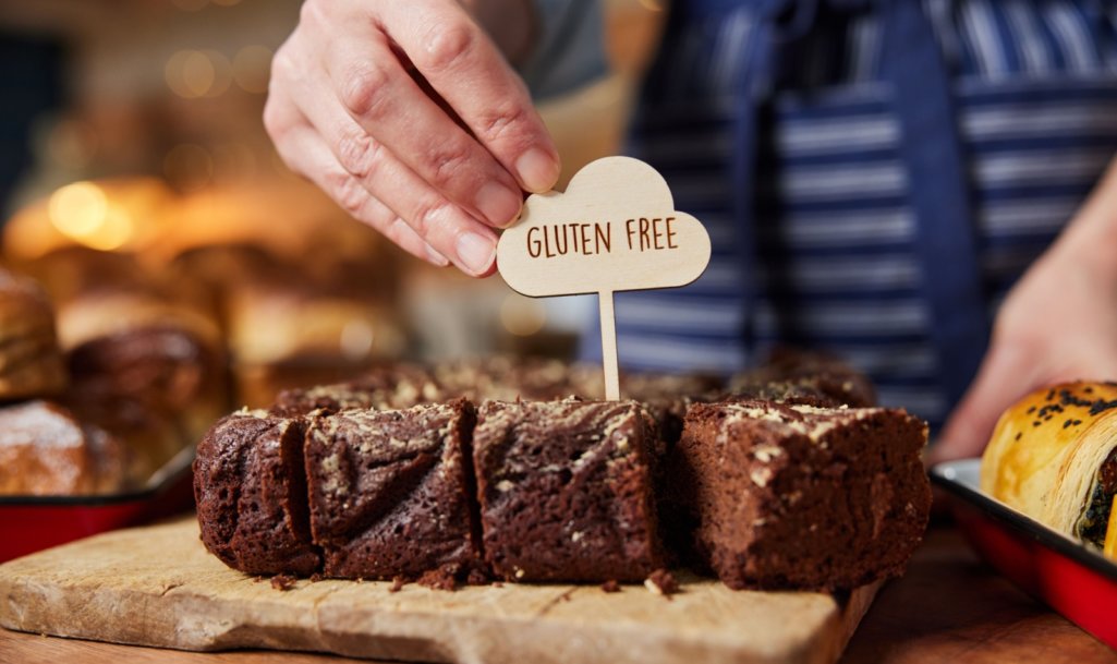 Sales Assistant In Bakery Putting Gluten Free Label Into Freshly Baked Brownies